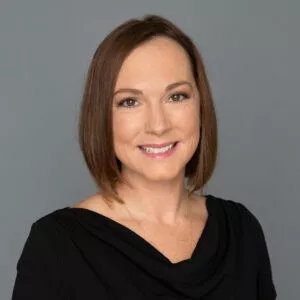 Headshot of Dr. Kimberly Riordan in professional wear with a grey background.