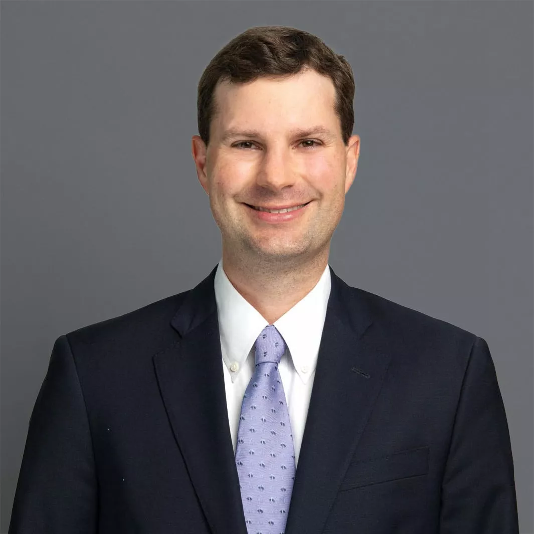 Headshot of Nathaniel Rieveschl, M.D. in professional wear with a grey background.