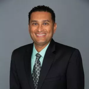 Headshot of Ravi Patel, M.D. in professional wear with a grey background.