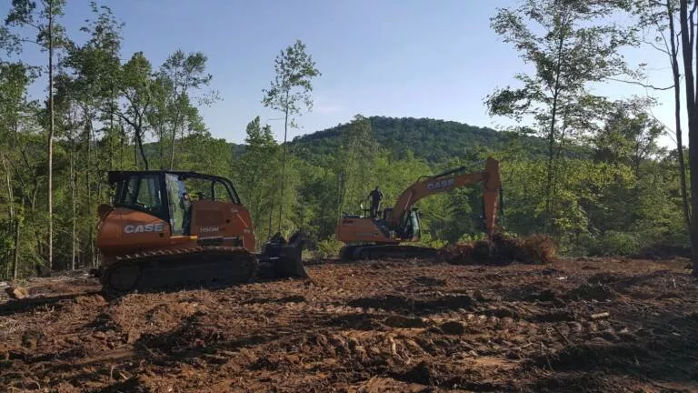 excavator and bobcat clearing land