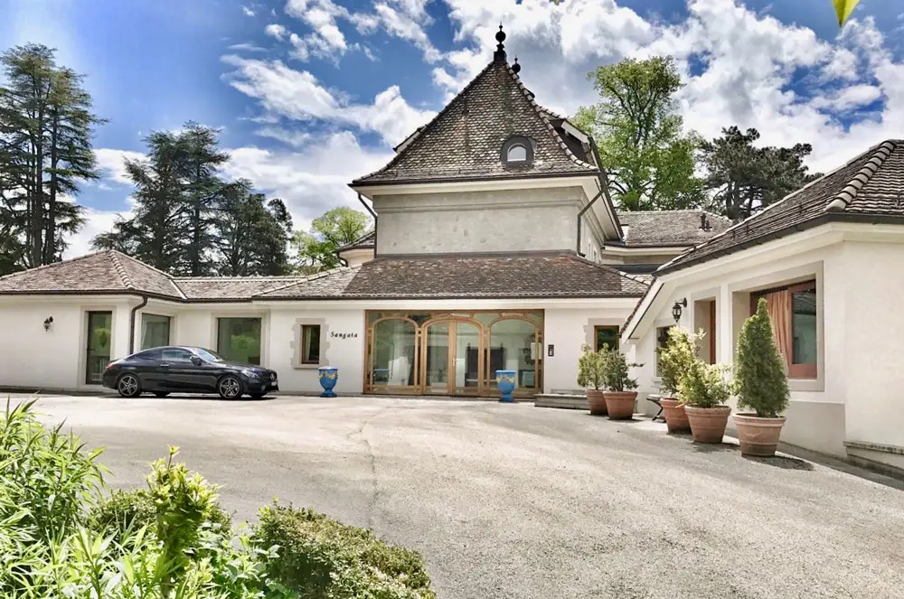 LEE_Buy Elegant white Geneva villa with arched entrance, luxury rental by GuestLee, potted plants, black car, Swiss sky backdrop. | GuestLee luxury rental Switzerland