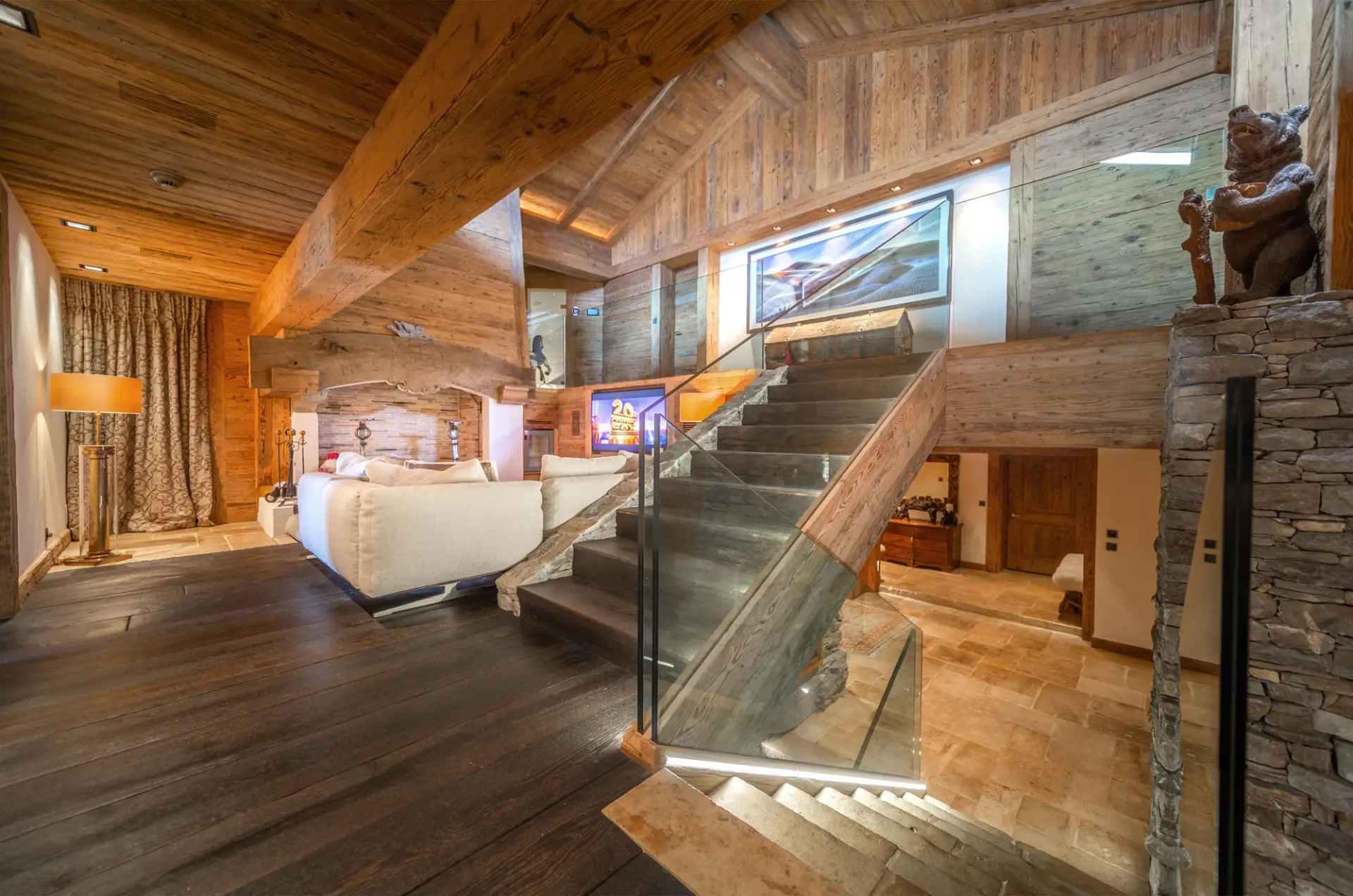 LEE_Rent Luxury Verbier chalet rental: wood interiors, glass staircase, stone details, white sofa, warm lights—perfect Swiss getaway. | GuestLee luxury rental Switzerland