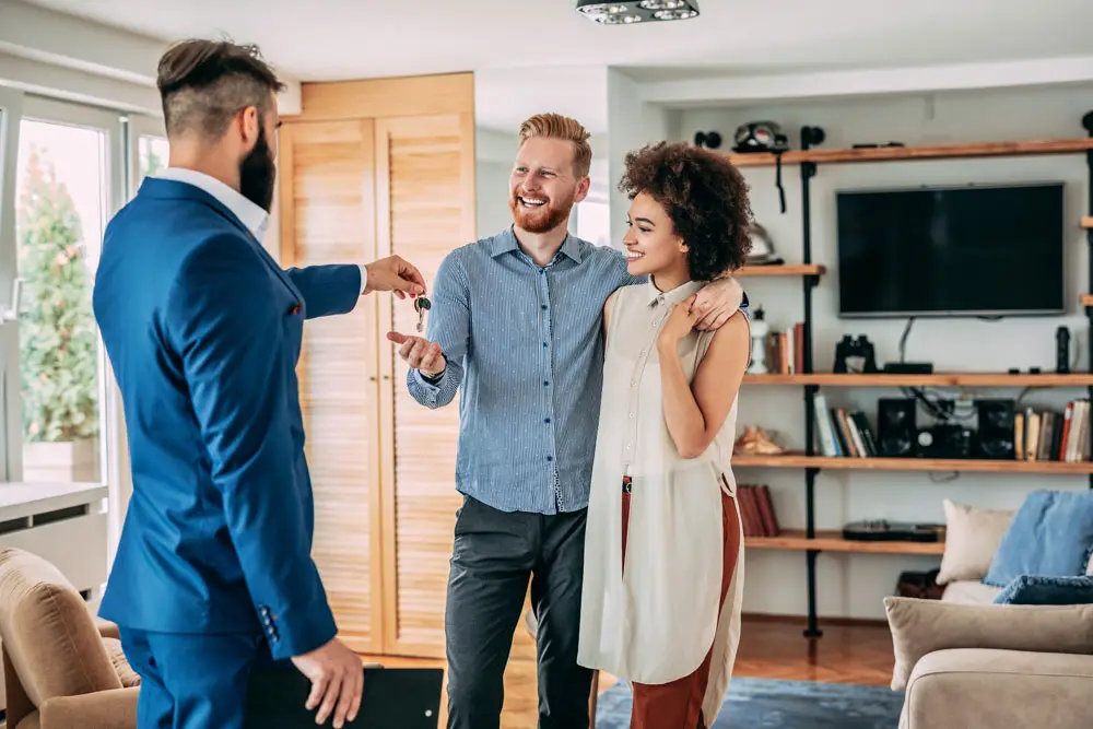 LEE_Sell GuestLee agent hands keys to a happy couple in a luxury Swiss rental living room in Geneva, Verbier, or Zermatt. | GuestLee luxury rental Switzerland