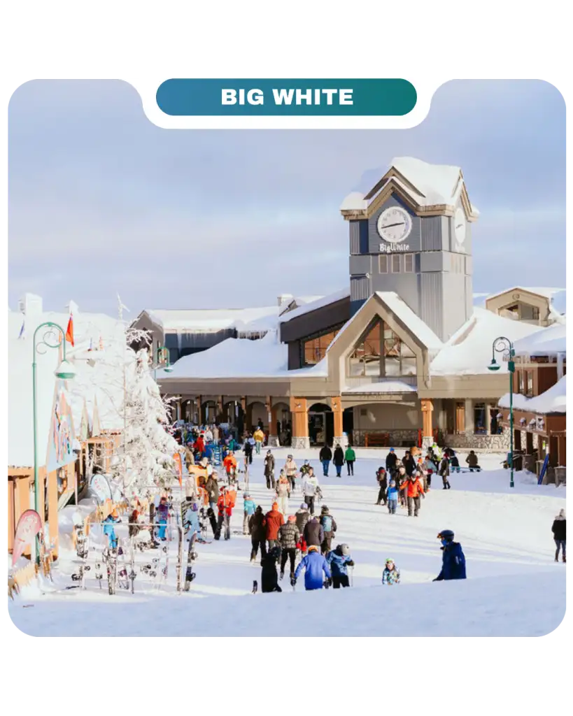 Crowds of people walk through a snow-covered village at Big White ski resort, home to Lifty Life, with a clock tower and charming buildings in the background under a cloudy sky.