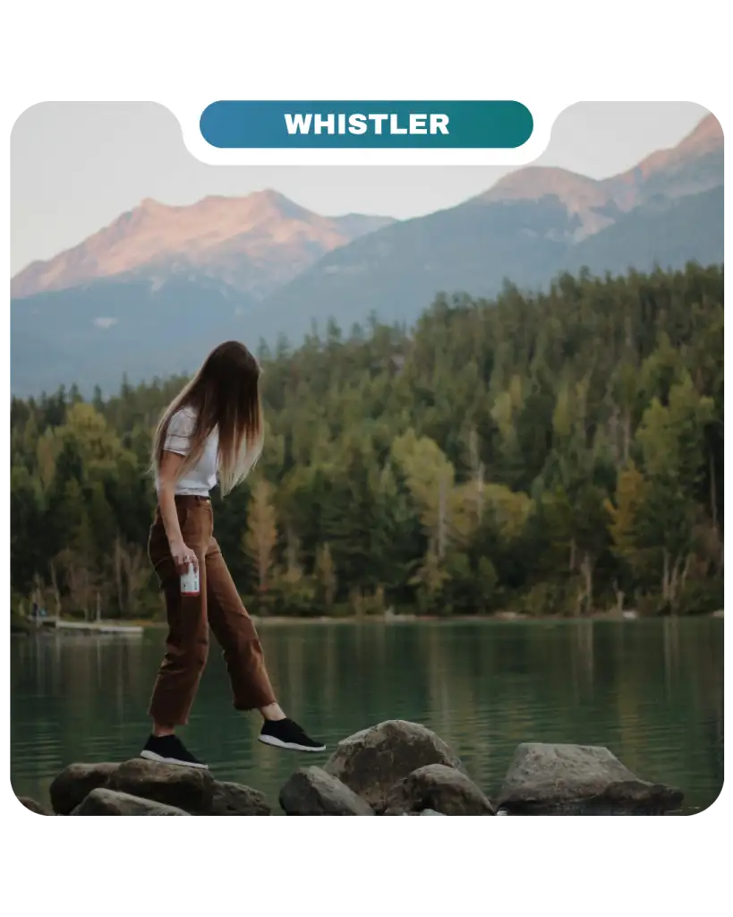A person stands on rocks by a lake surrounded by trees and mountains, with a "Whistler" label at the top and a subtle nod to Lifty Life adventure in the fresh mountain air.