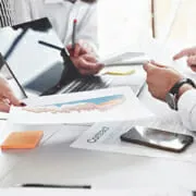 Two people with laptop looking over printed documents.
