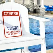 Lifeguard char beside pool with No Lifeguard on Duty warning sign
