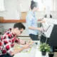 A man sitting at a table looking at a color chart while a woman operates a printing machine.