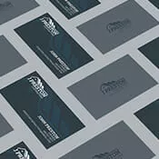 Business cards are displayed on a grey table showing the front and back of the cards.