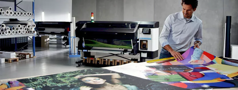Man at a commercial printing company looking at printed posters.