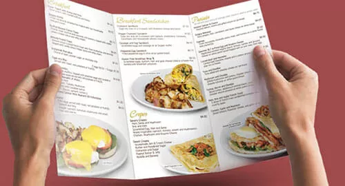 PRI_Menu&Tags-Page-Breakfast-Menu Hands holding a trifold breakfast menu.