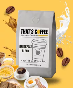A gray bag labeled "That's Coffee Breakfast Blend," part of our premium coffee blends, is surrounded by coffee beans, a breakfast spread, and a splash of milk on a vibrant yellow background.