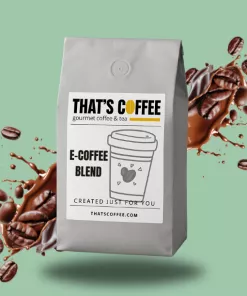 A gray bag of "THAT'S COFFEE" E-Coffee Blend sits in front of a green background, surrounded by rich coffee blends, coffee beans, and a dynamic splash of coffee.