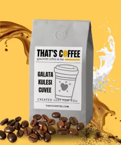 A gray coffee bag labeled "That's Coffee Galata Kulesi Cuvee" stands amid spilling coffee, milk splashes, scattered coffee beans, and hints of premium coffee blends on a vibrant yellow background.