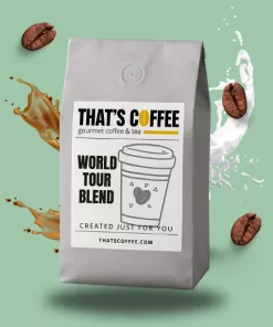 A gray bag of THAT'S COFFEE World Tour Blend sits upright; coffee blends, whole beans, and splashes of milk swirl around it on a green background.