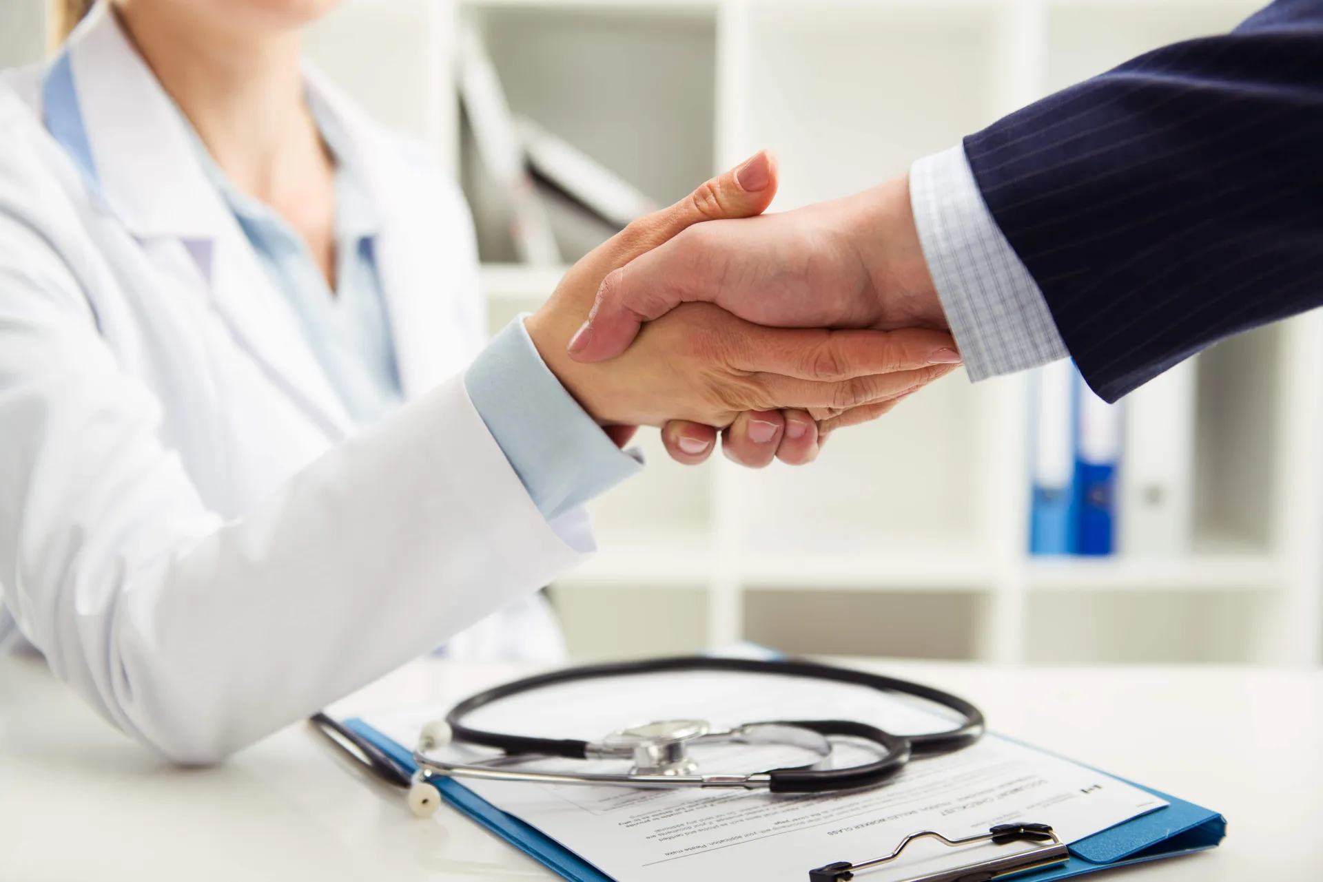 Woman doctor shaking hand with businessman in the office Woman doctor shaking hand with businessman in the office