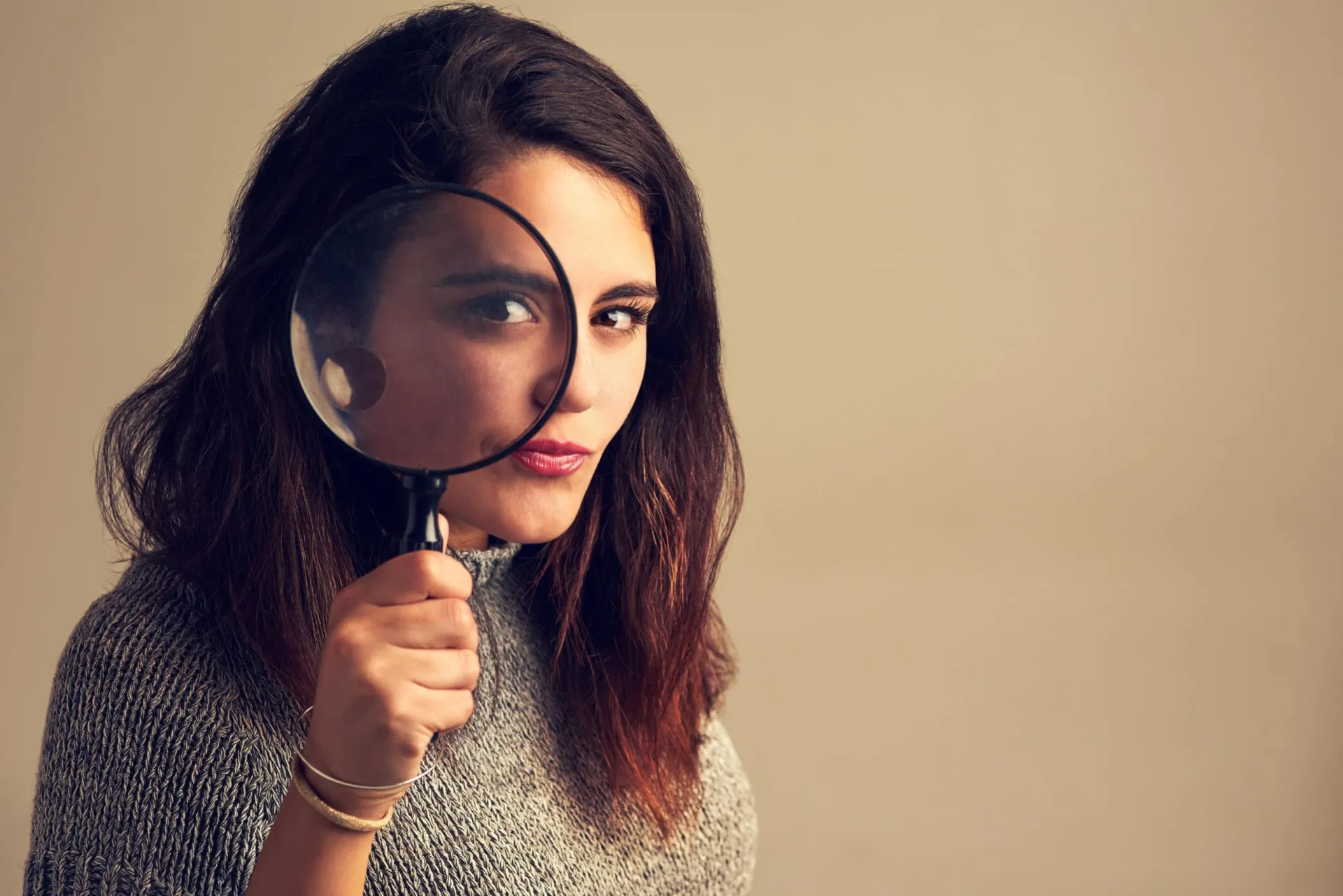 Market Research Detective Woman holding magnifying glass, analyzing sales and marketing data.