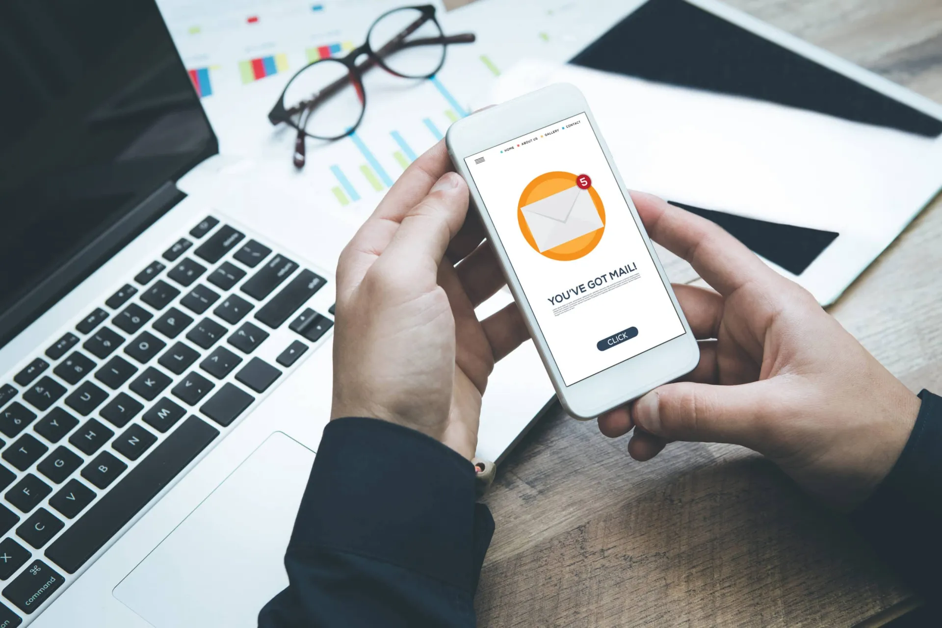 Email Marketing and Outbound Calling Strategy Person checking email on smartphone with work desk background.