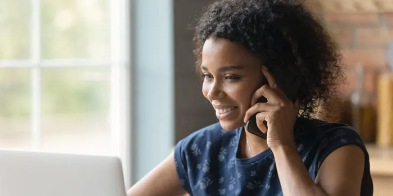 Woman on phone working on laptop, promoting lead nurturing for business growth.