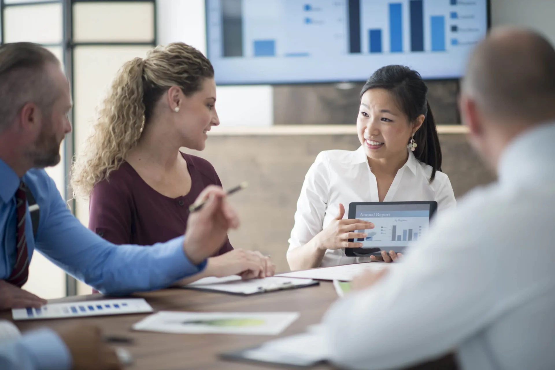 Healthcare Lead Generation Strategies Business team discussing healthcare lead generation metrics with tablet display.