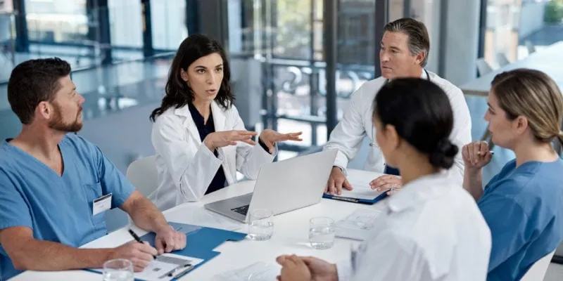 Medical professionals discussing sales strategies in a modern conference room.