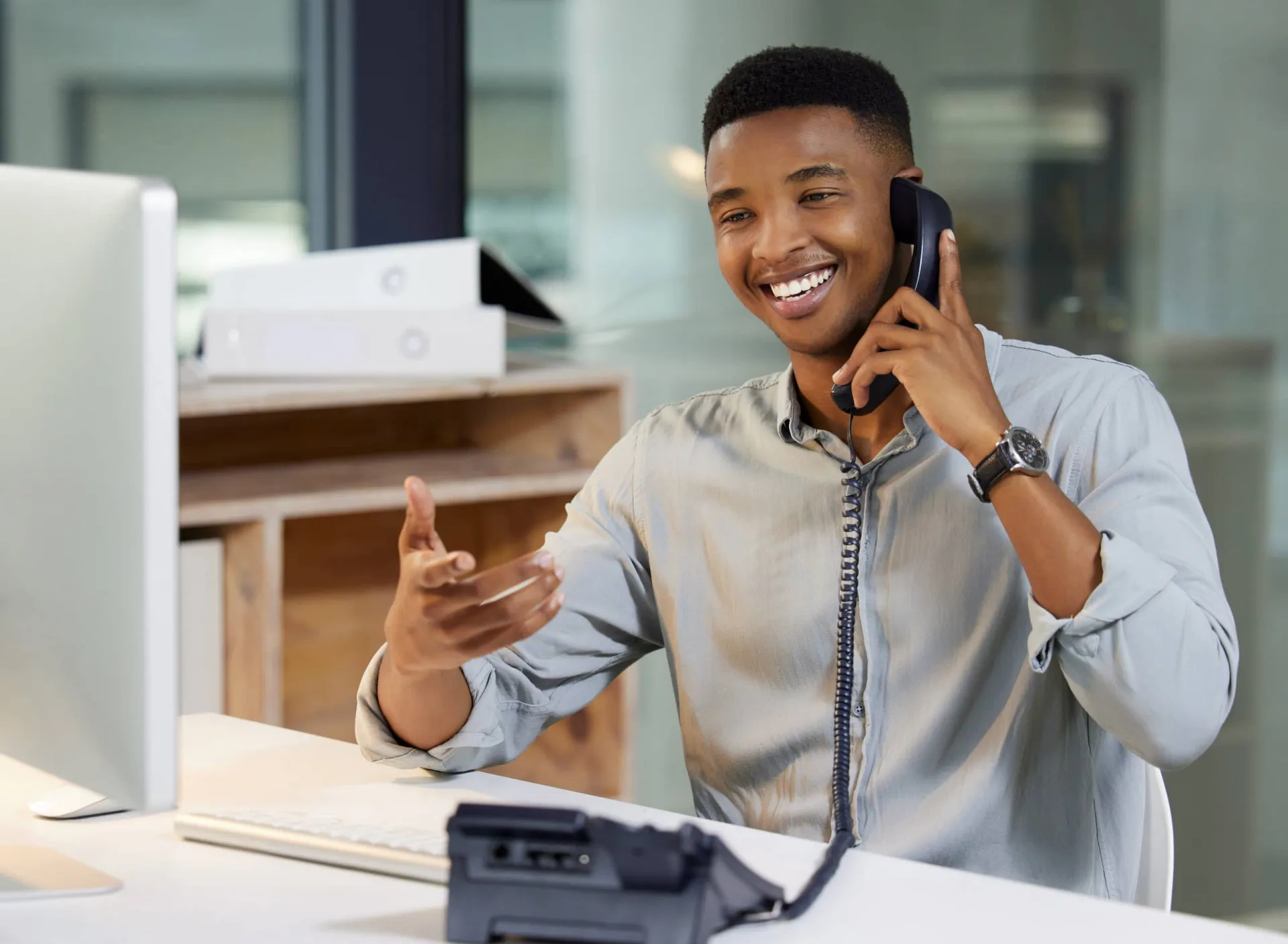 Sales professional making a call at his desk. Sales professional on a business call, smiling and engaging with a client.