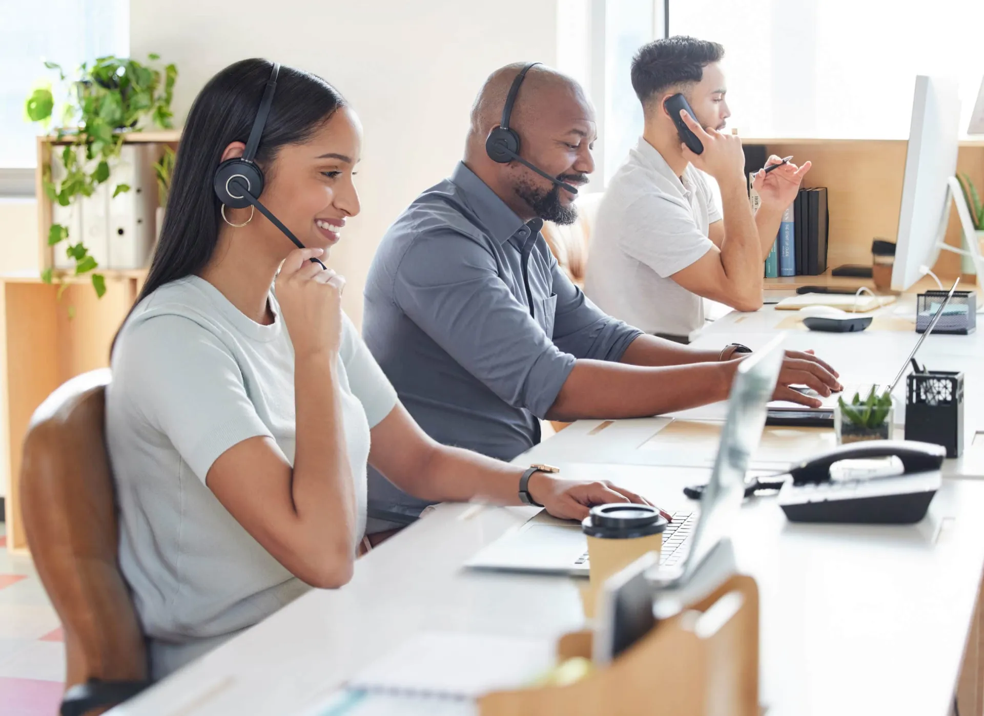 Customer support team handling inside sales calls remotely. Remote inside sales support team with headsets working at desks.