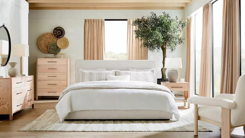 A bedroom scene with lightwood furniture and white bedding