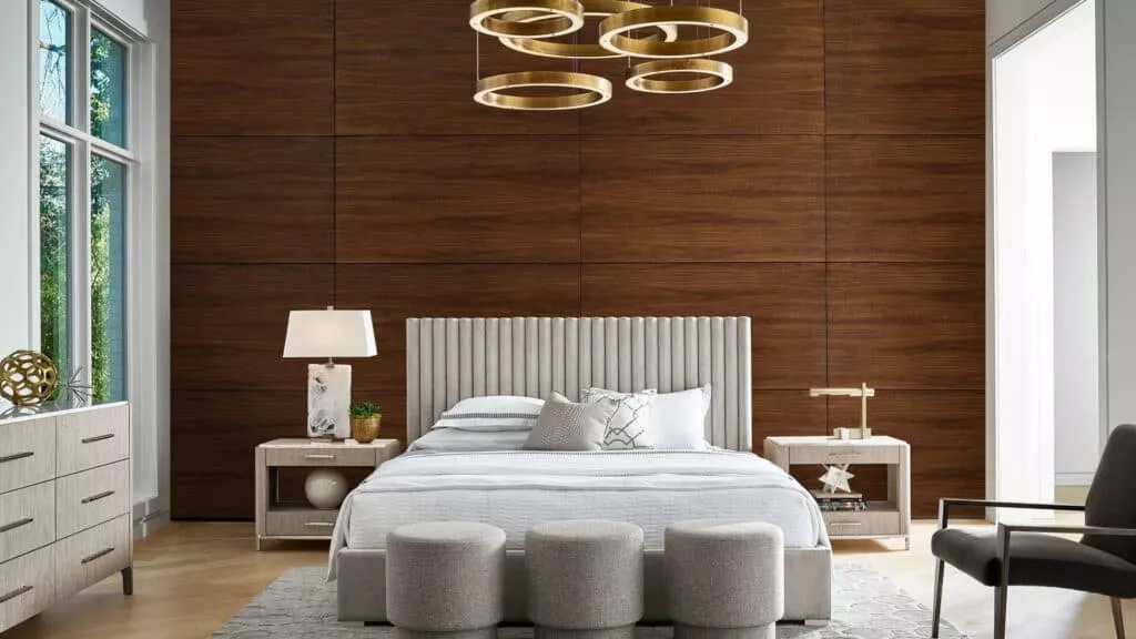 A bedroom with a wood panel wall, a circular light fixture, and circular storage units at the foot of the bed.