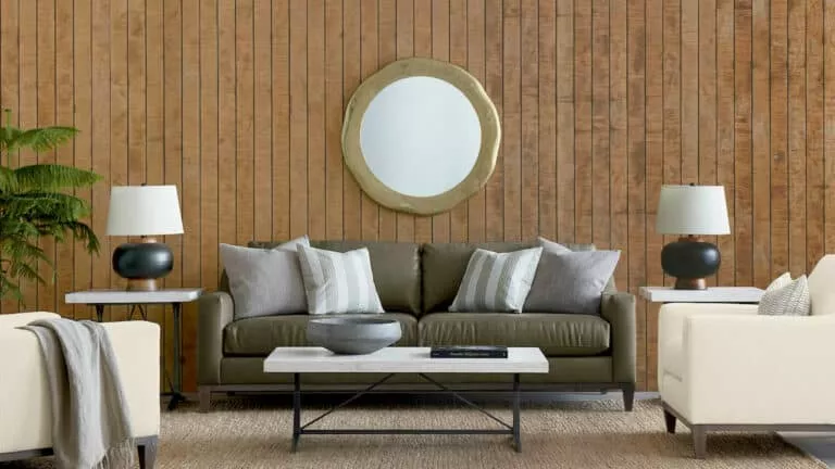 A gray leather couch in a living room with wood panel walls