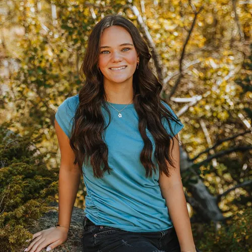 Young woman poses next to a gold-leafed Aspen tree