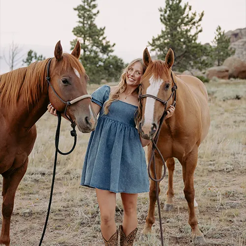 Lerwick_Hattie_Gold A young woman leans against one of two horses standing side by side